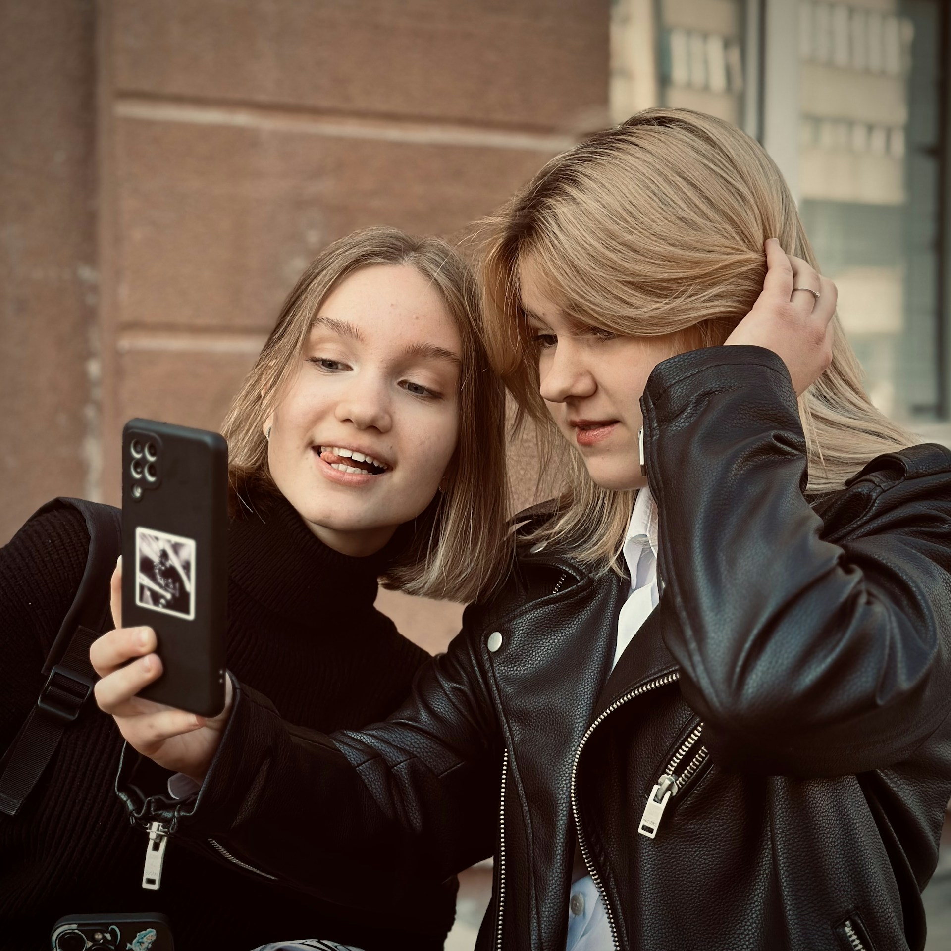 Two girls are looking at a cell phone