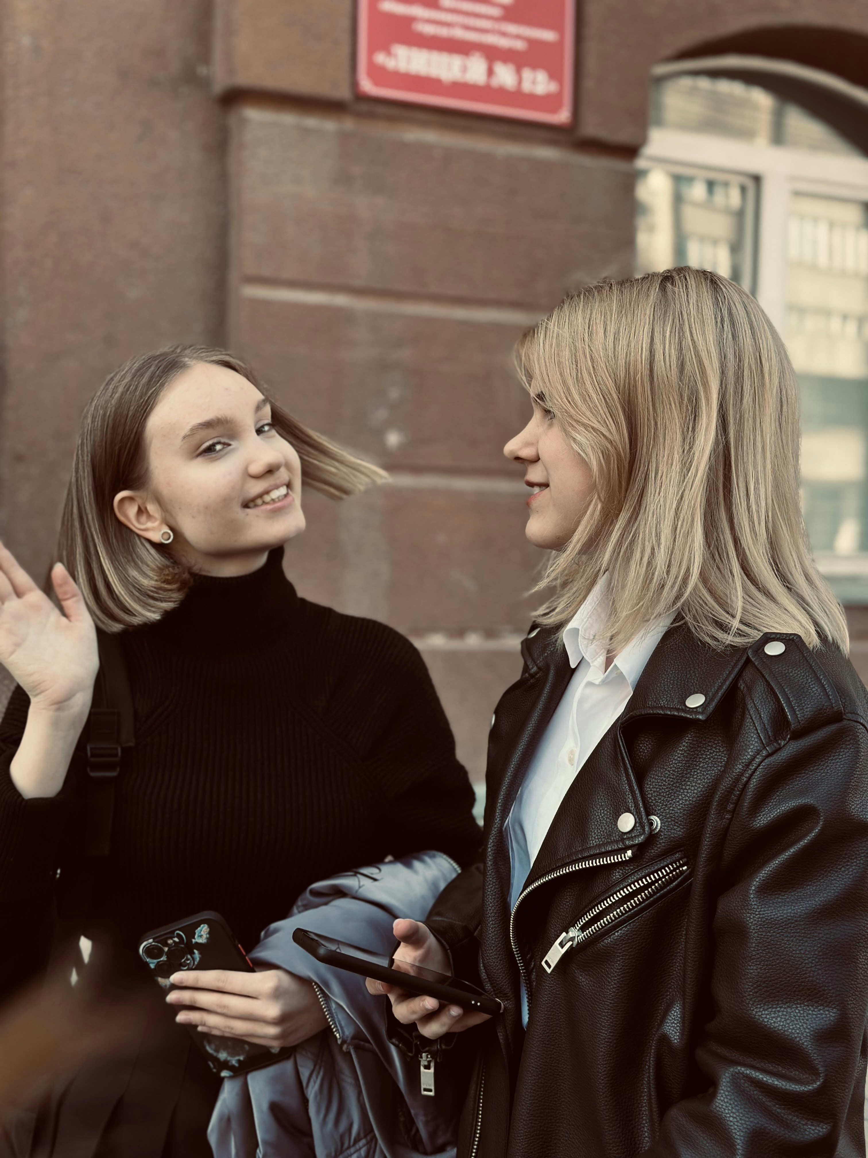 Two women standing next to each other in front of a building
