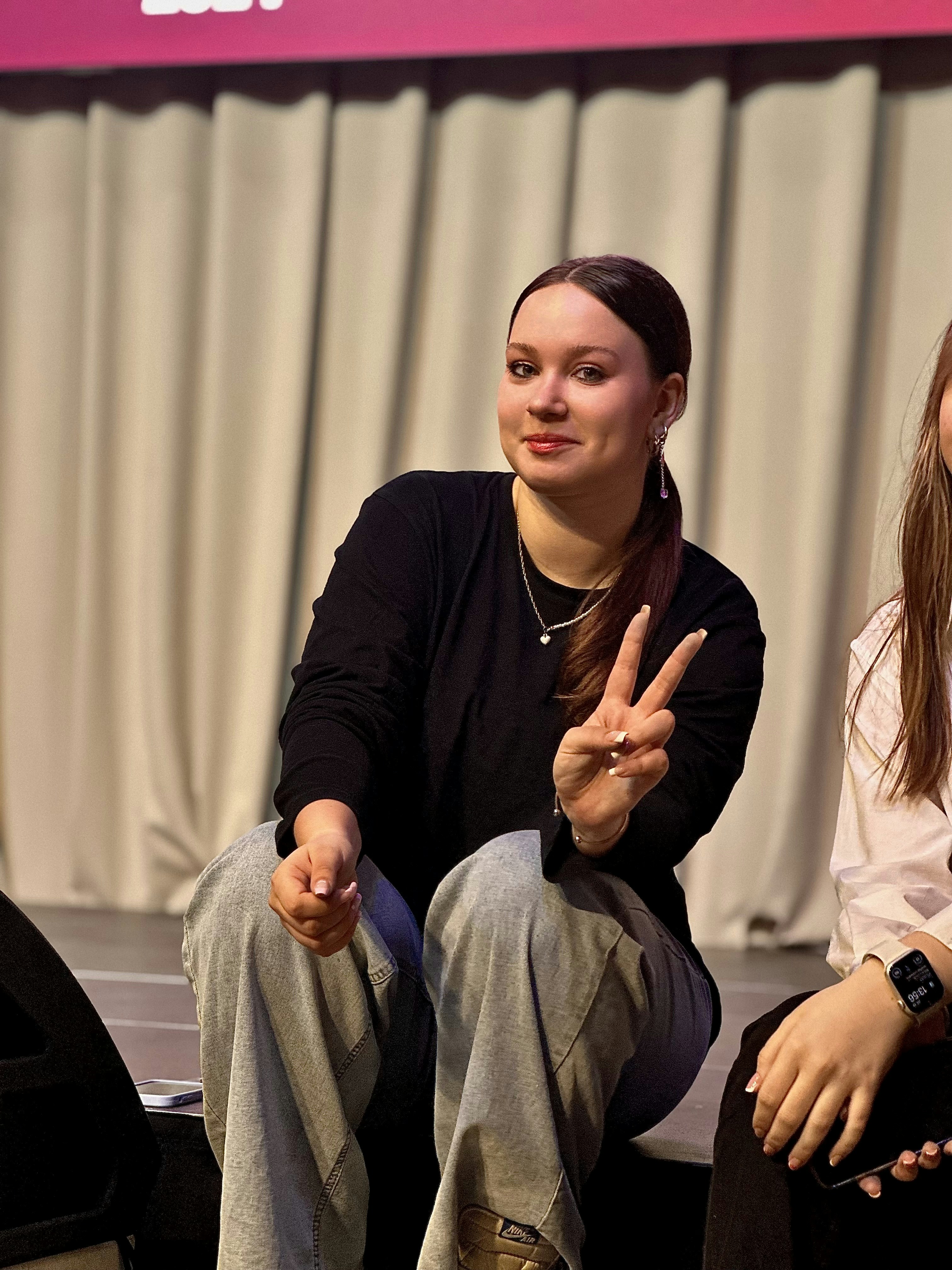 Two women sitting on a stage with their hands in the air