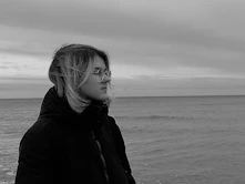 A woman standing on a beach next to the ocean