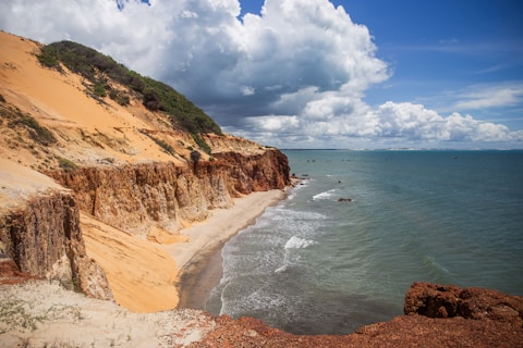 A sandy beach next to the ocean under a cloudy sky