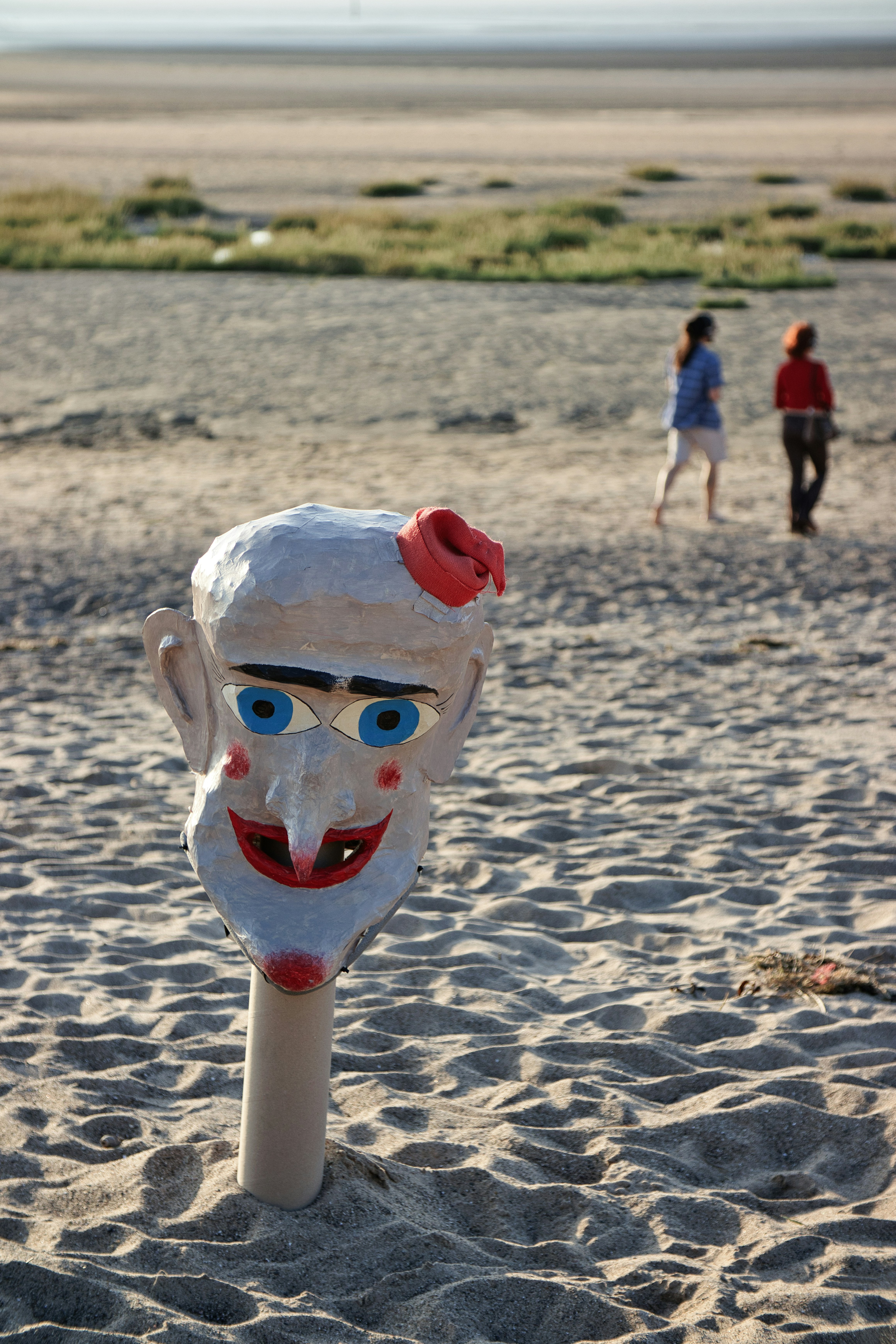 A mask is sticking out of the sand on a beach