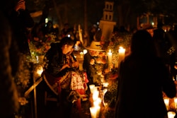 A group of people standing around a bunch of candles