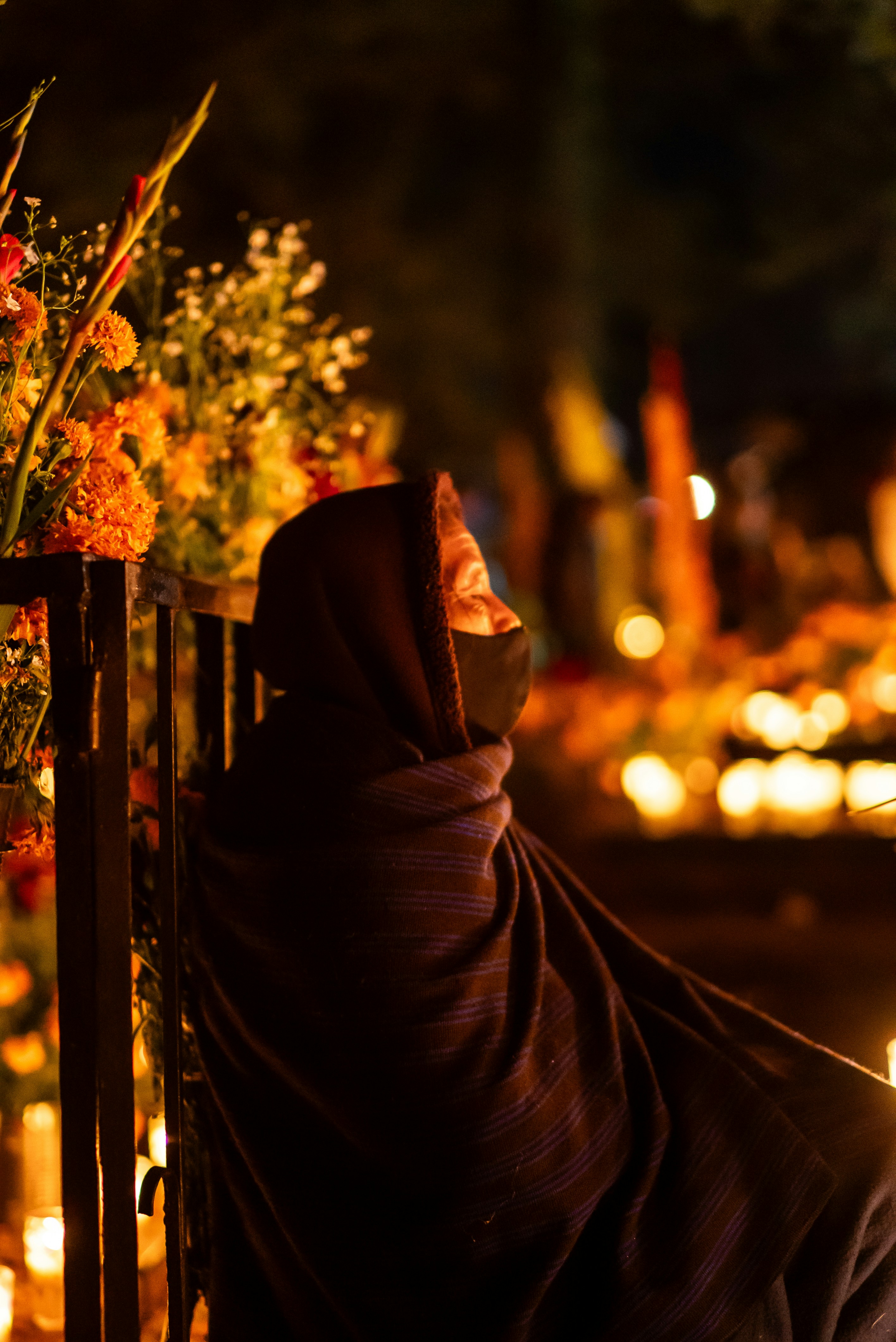 Eine Frau in einem Schal sitzt auf einem Zaun