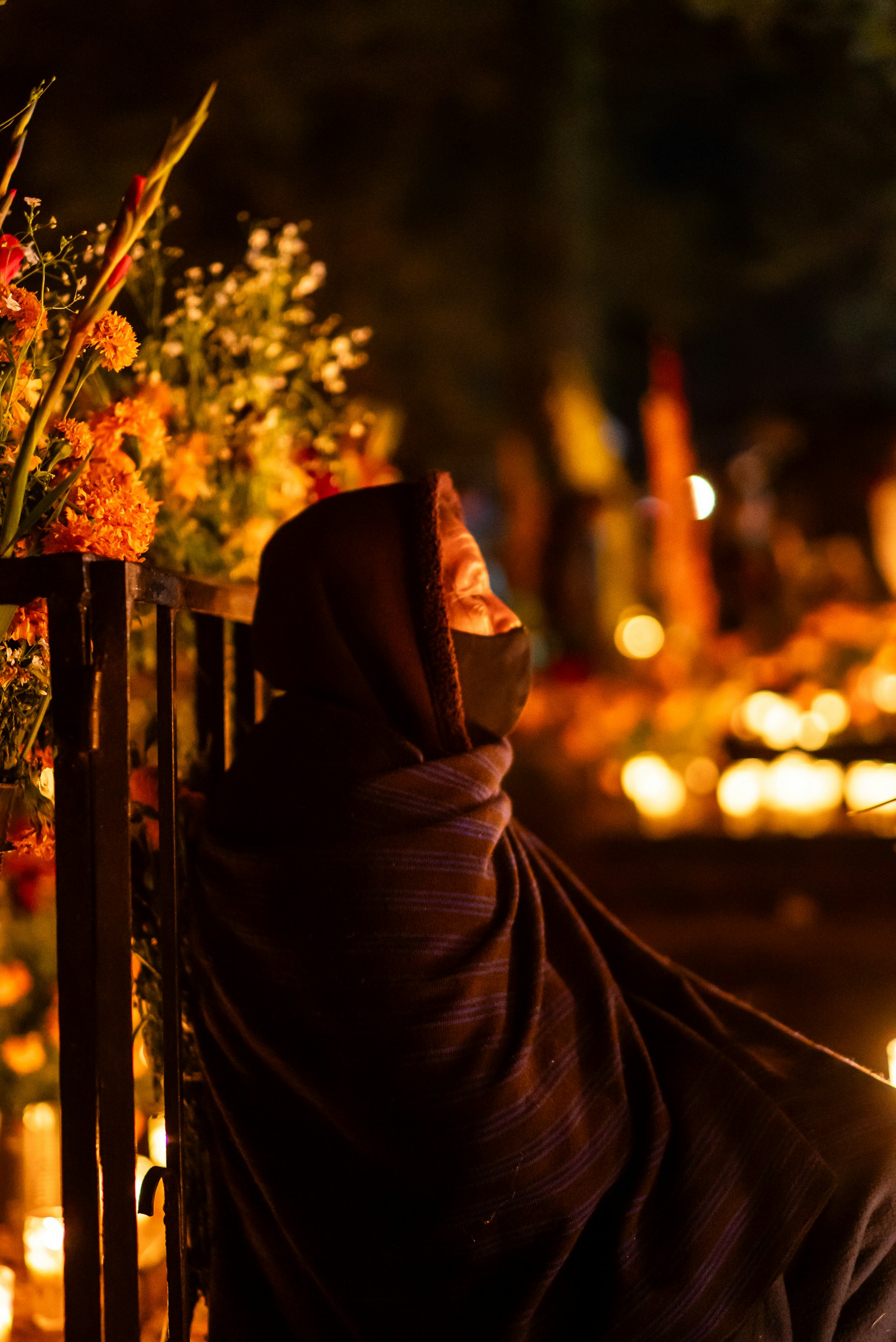 A woman in a shawl sitting on a fence