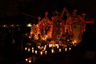 A group of people standing around a church with candles in front of it