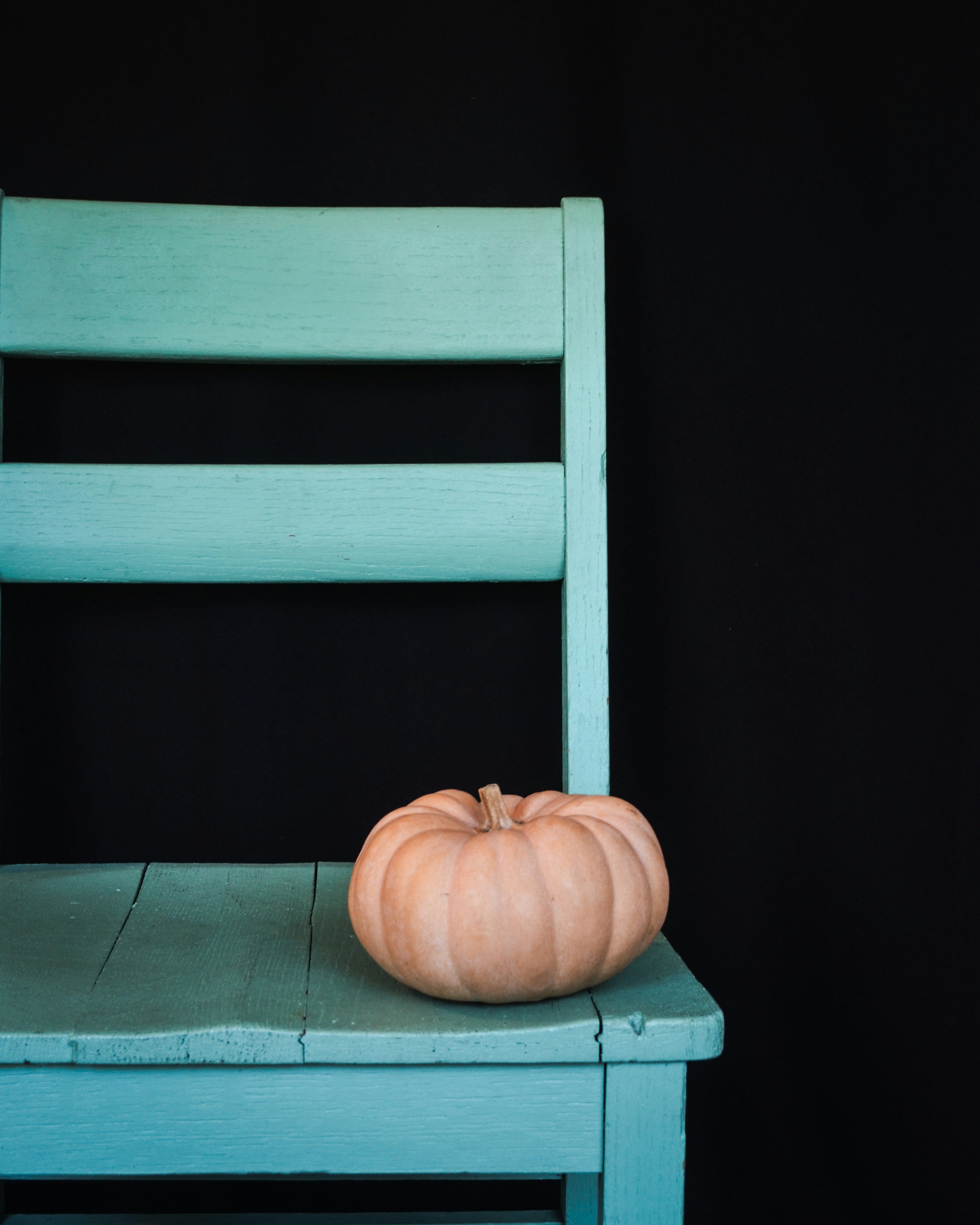 A blue chair with a pumpkin sitting on top of it