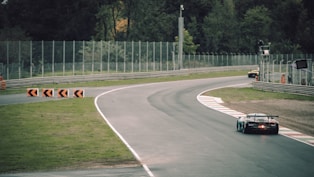 A car driving on a race track near a fence