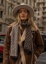 A woman in a hat and scarf standing on a street