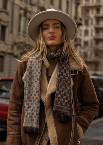 A woman in a hat and scarf standing on a street