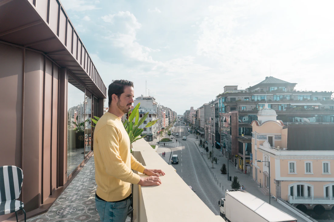 A man standing on a balcony looking out over the city