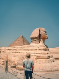 A torist standing in front of a large sphinx