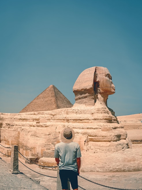 A man standing in front of a large sphinx
