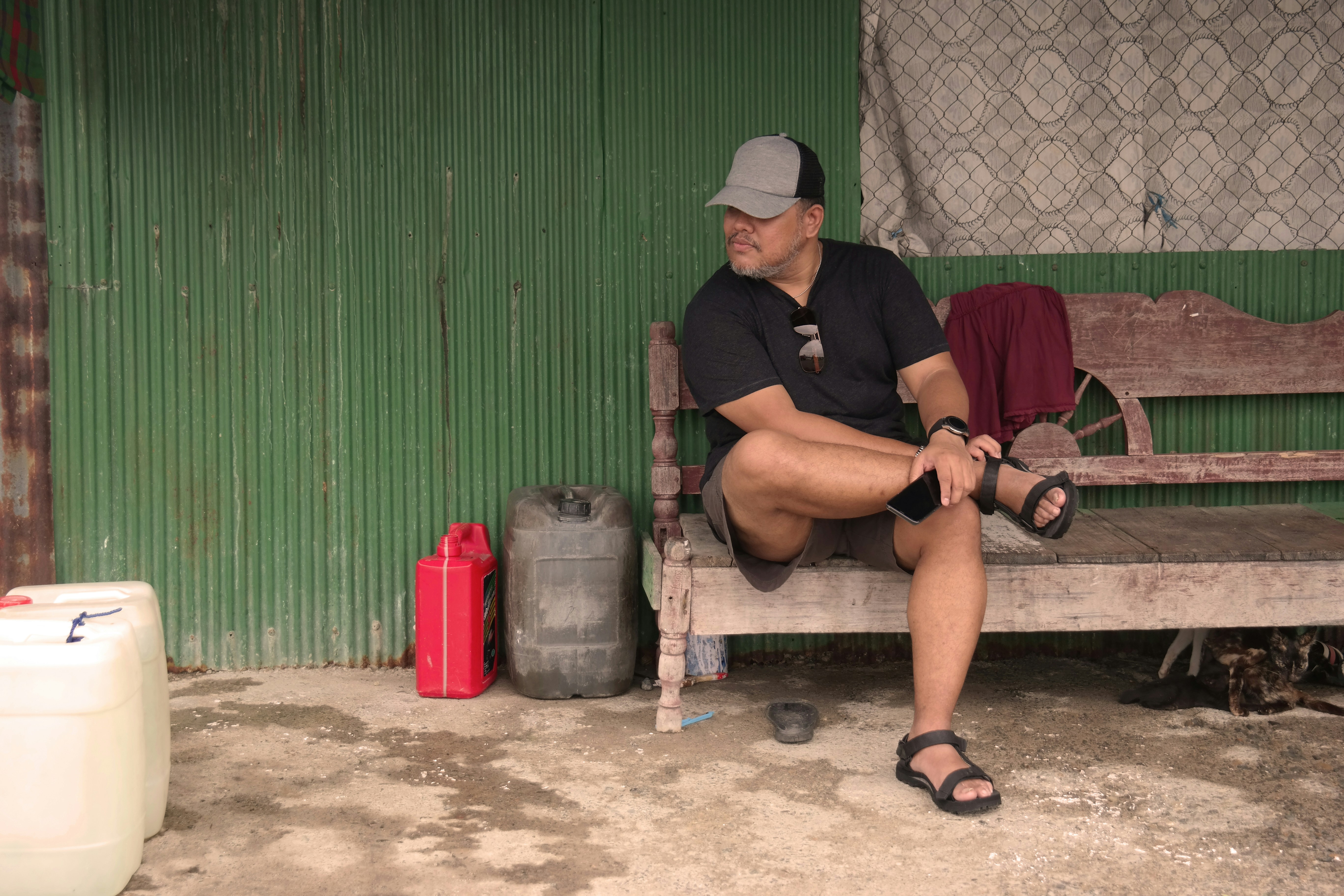 A man sitting on a bench in front of a green building