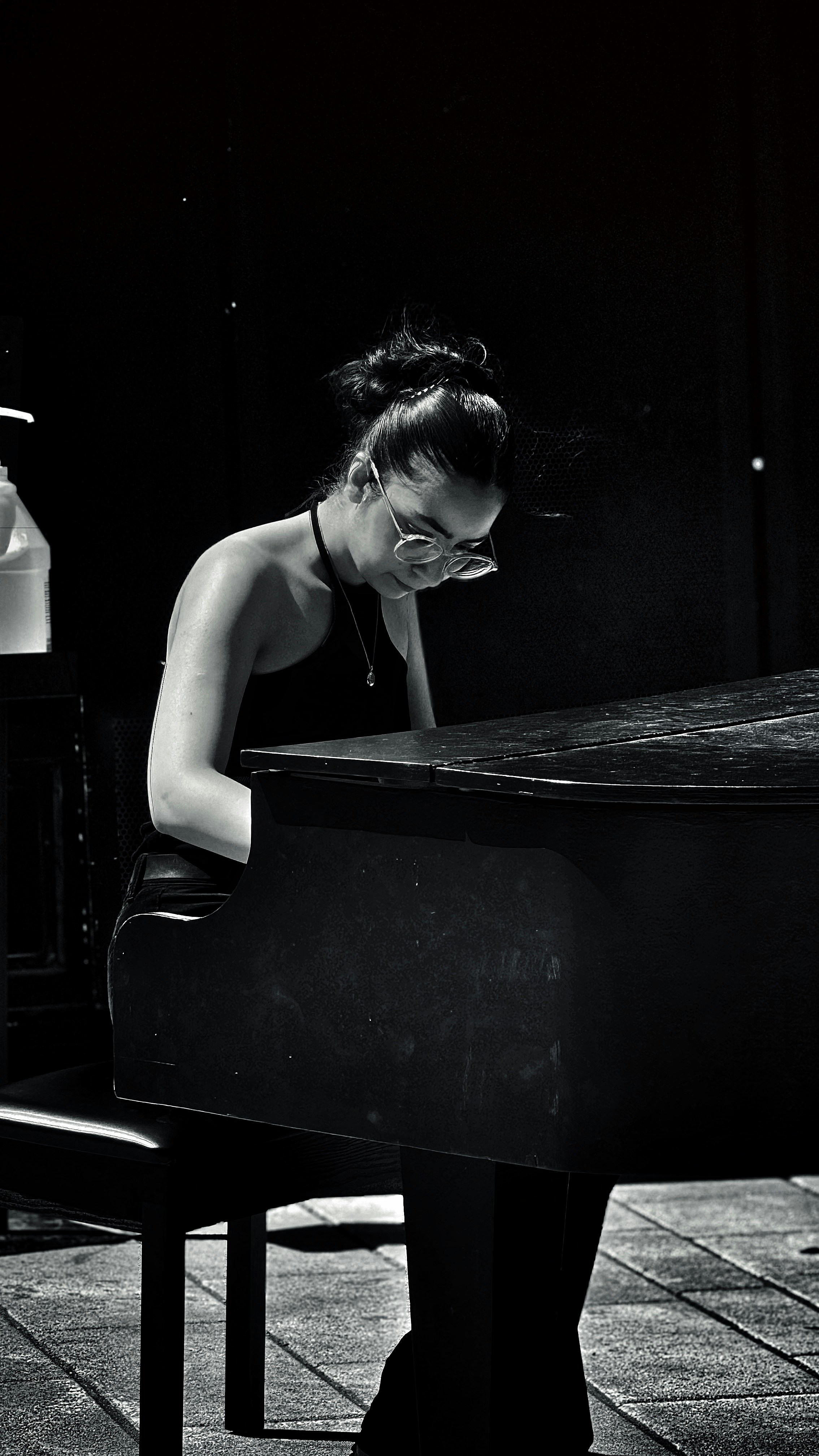 Uma foto preto e branco de uma mulher que senta-se em um piano