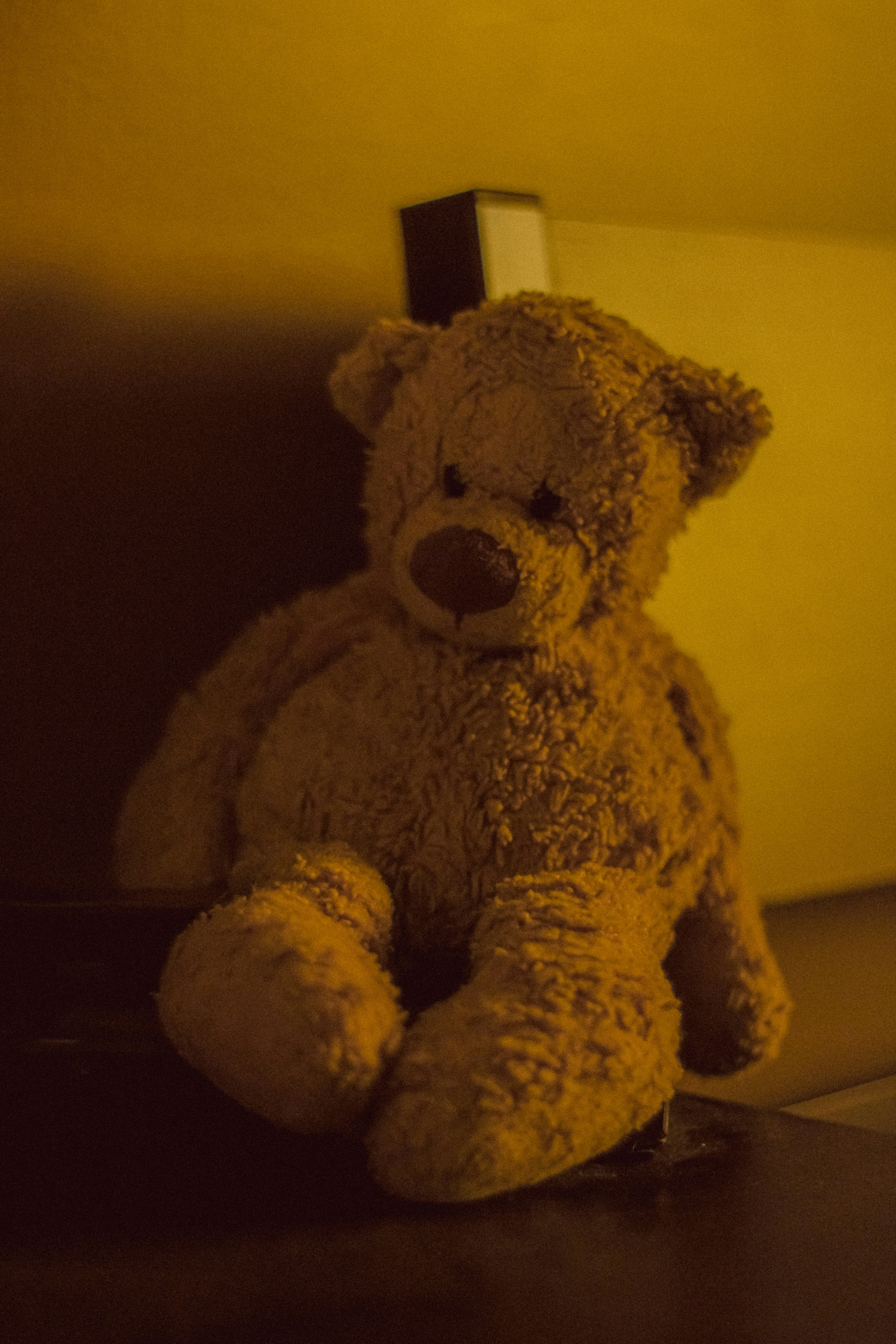 teddy bear by bedside in nostalgic yellow light