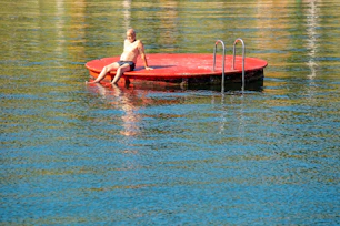 A man sitting on a floating platform in the middle of a lake