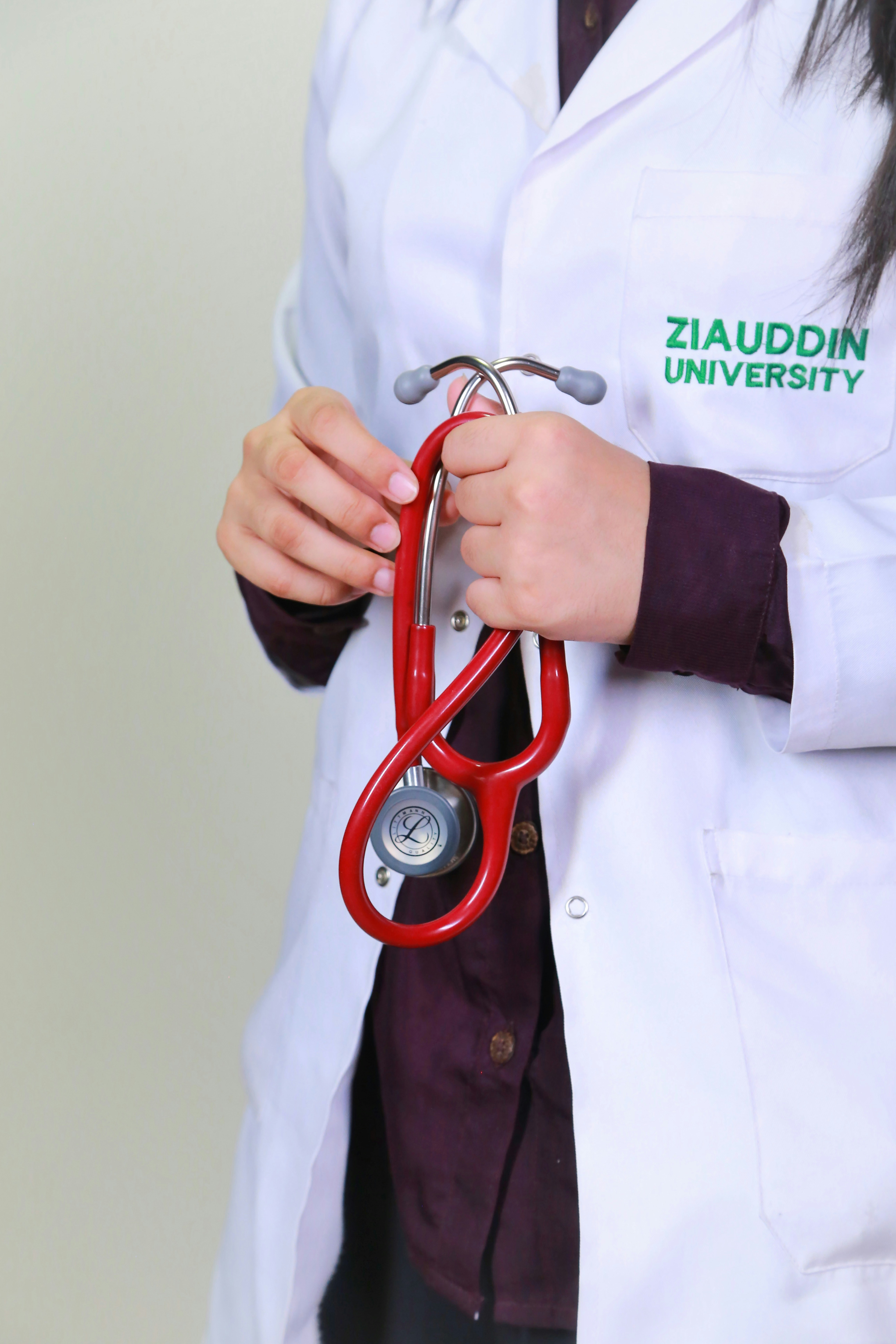 A woman in a white lab coat holding a red stethoscope