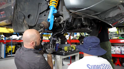 Two men working on a car in a garage