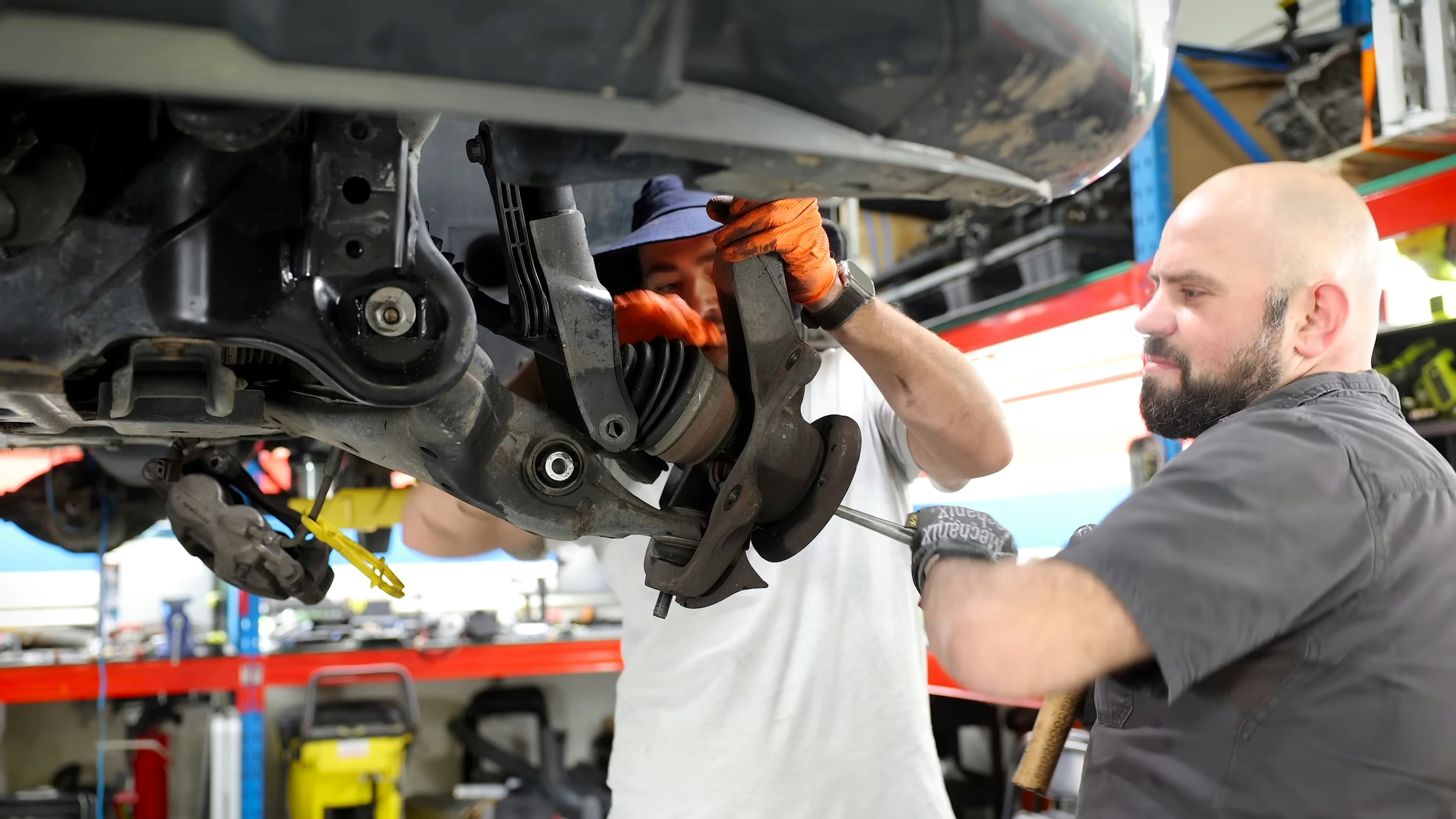 Technician inspecting the tires and wheels of an electric crossover in a service bay