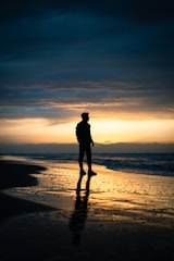 A man standing on top of a beach next to the ocean