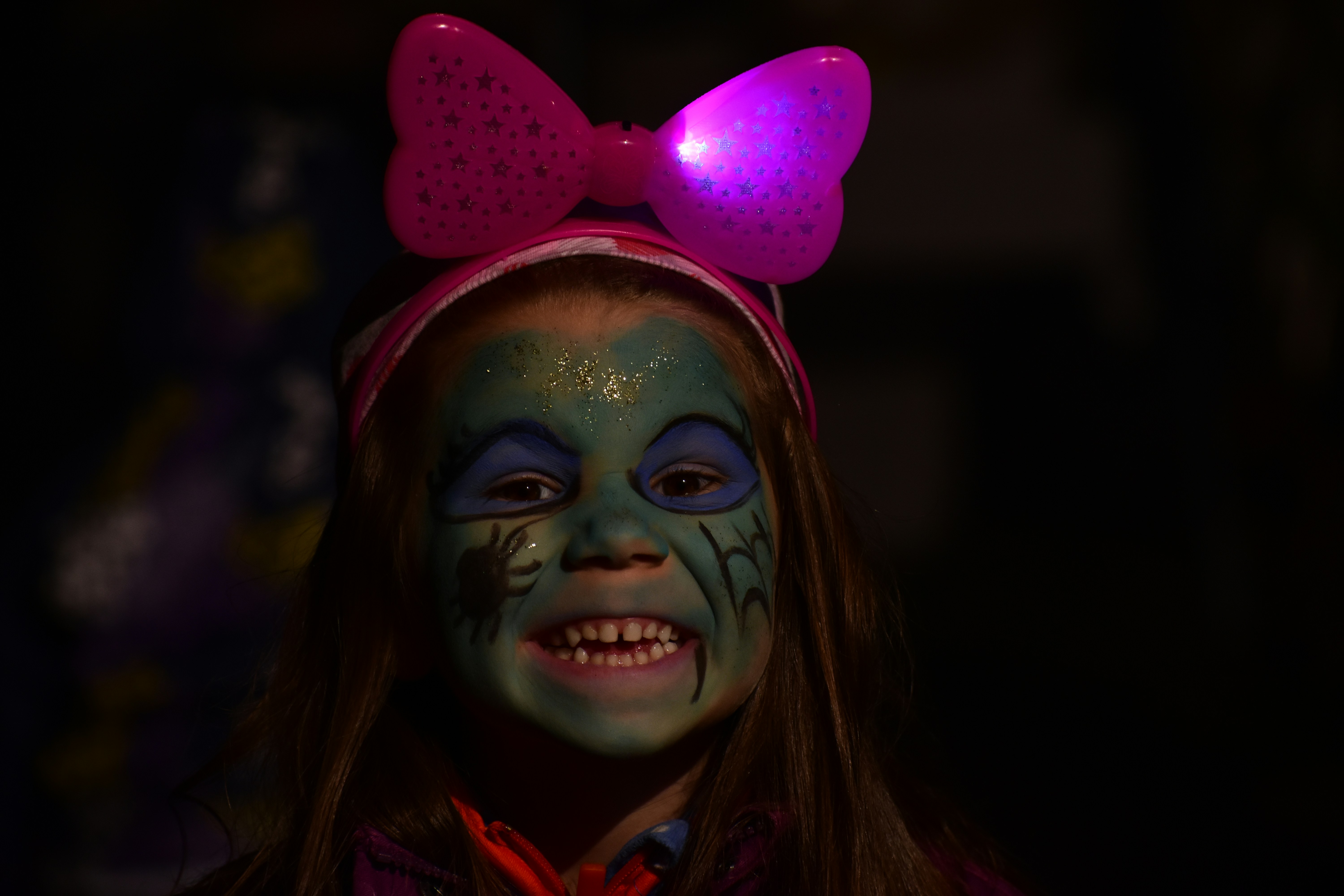 A young girl with face paint and a bow on her head