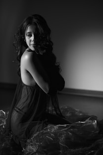 A woman in a black dress sitting on a bed