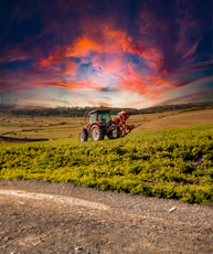 A tractor in a field with a sunset in the background
