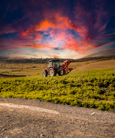 A tractor in a field with a sunset in the background