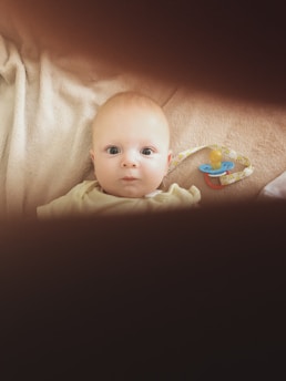 A baby laying in a crib looking at the camera