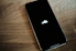An iPhone sitting on a wooden table with an apple logo on it