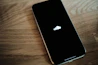 An iPhone sitting on a wooden table with an apple logo on it