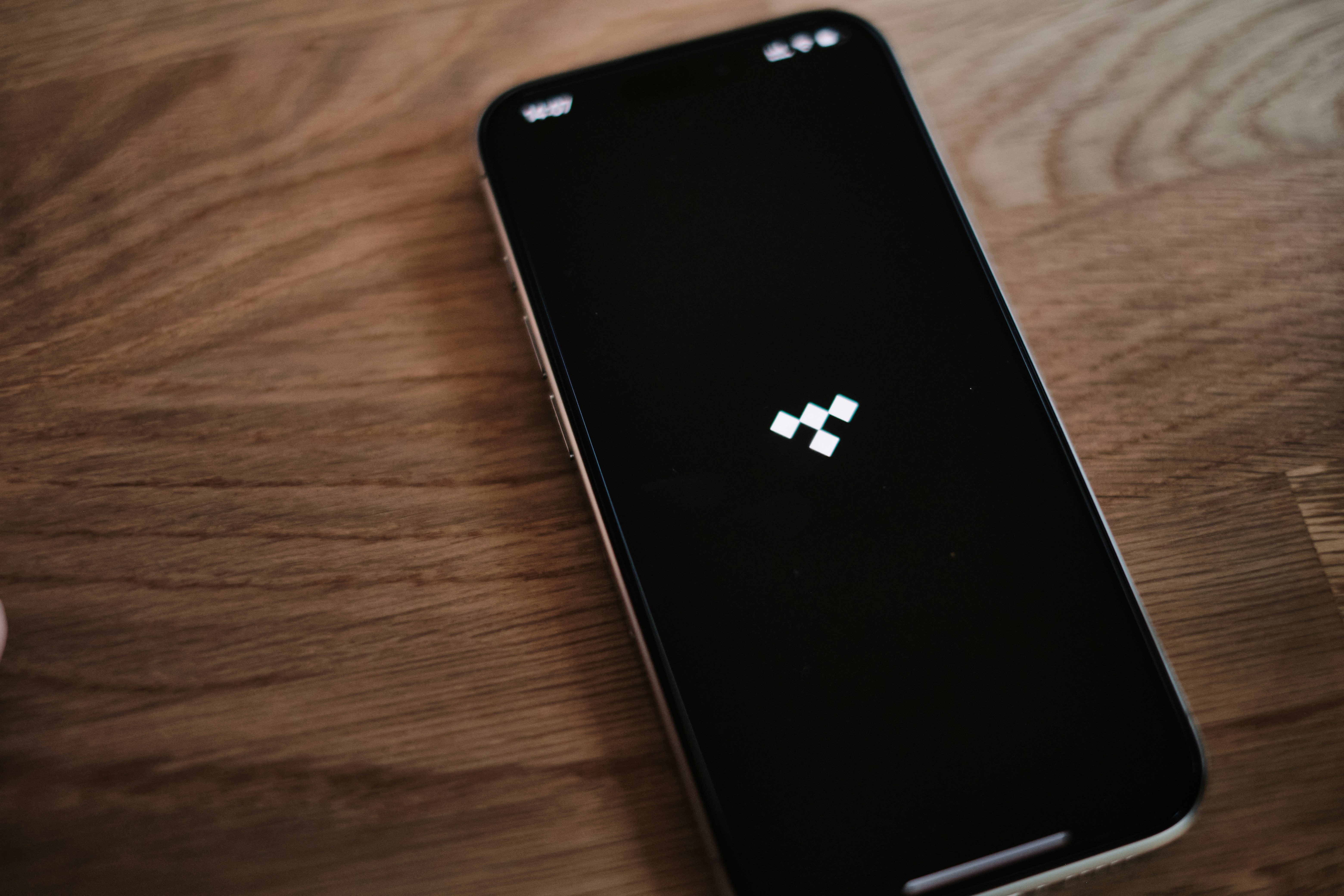 A black cell phone sitting on top of a wooden table