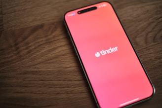 A pink iPhone sitting on top of a wooden table