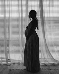 A pregnant woman standing in front of a window