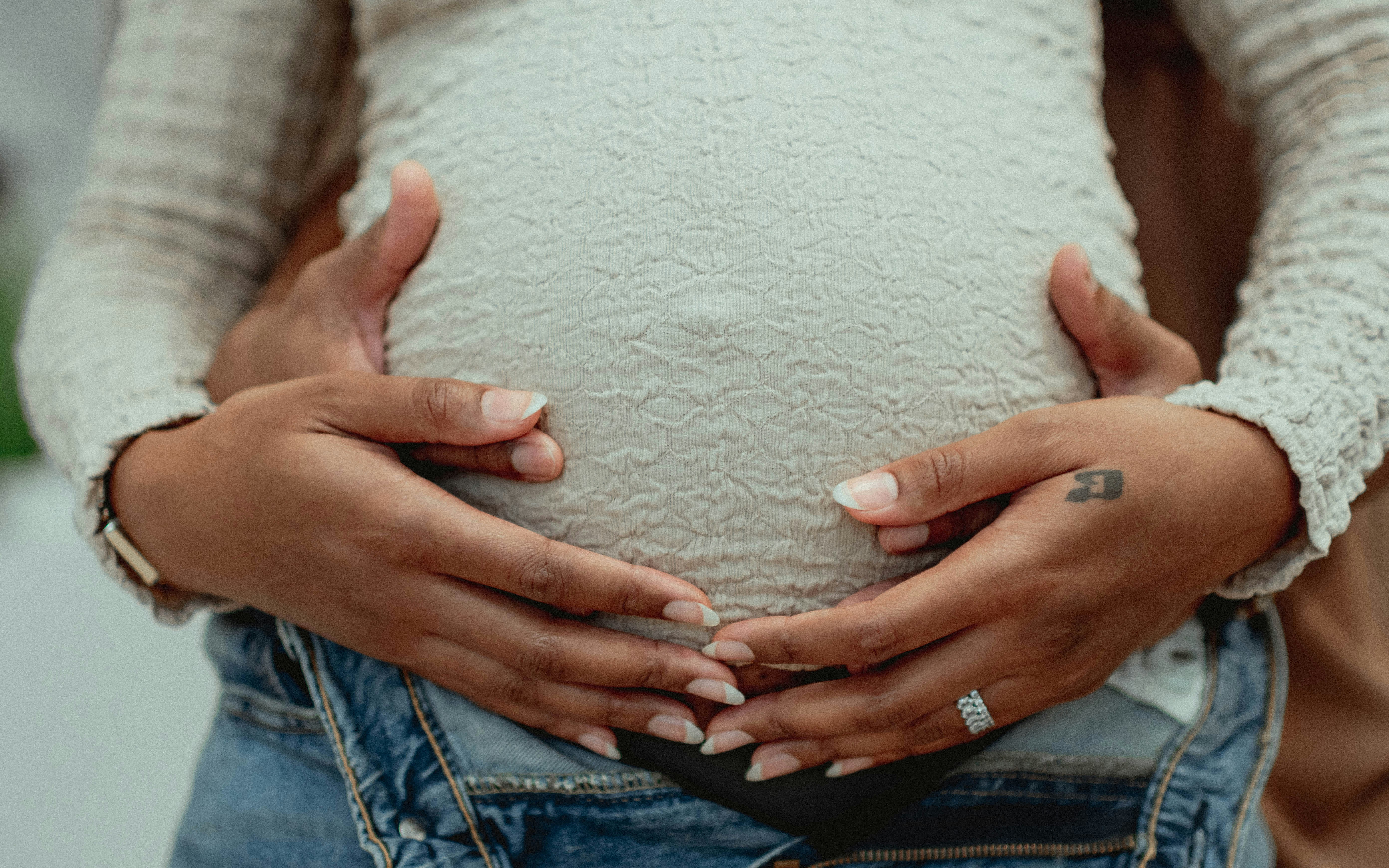 Pregnant woman holding her belly with both hands