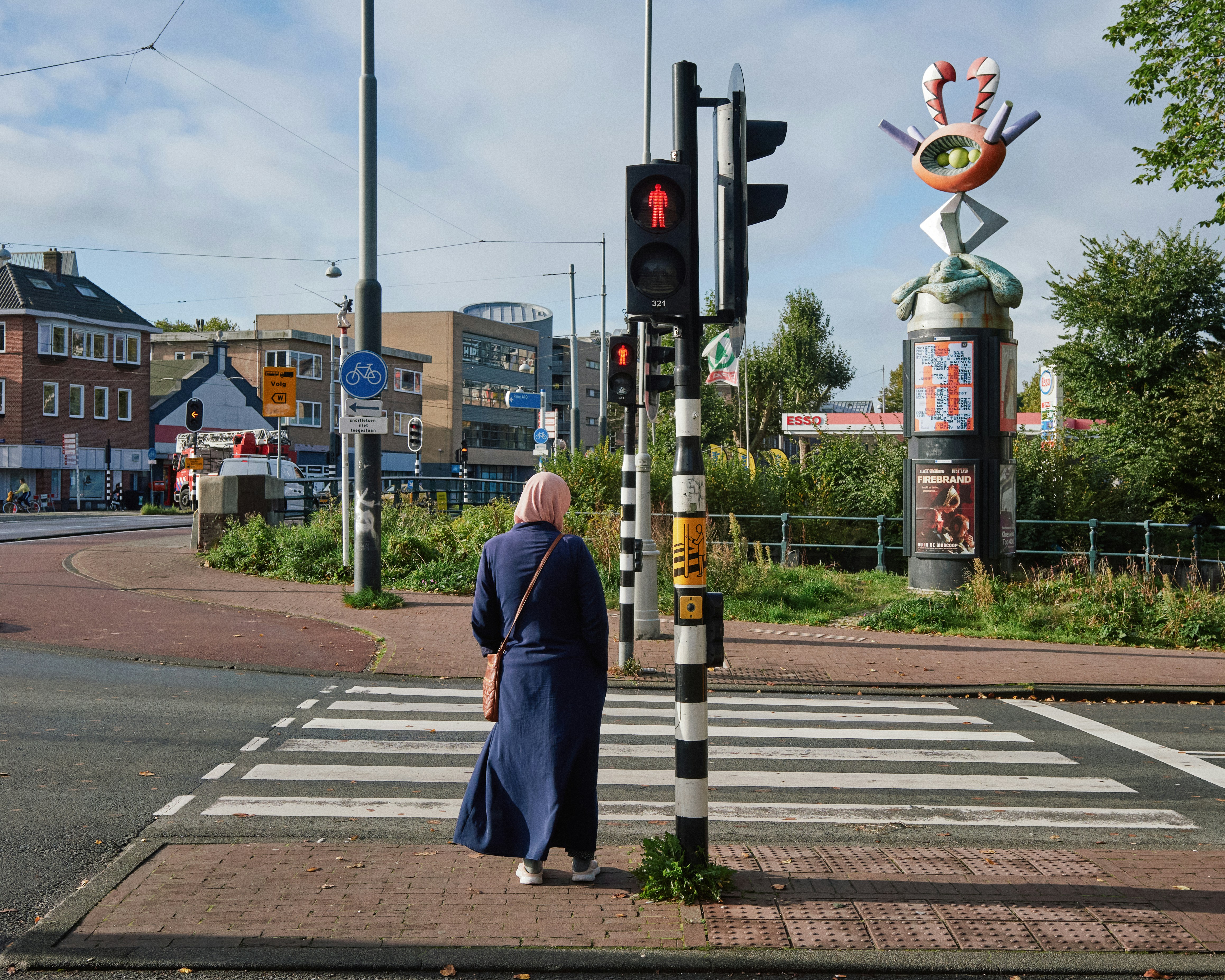 A man standing on a street corner next to a traffic light