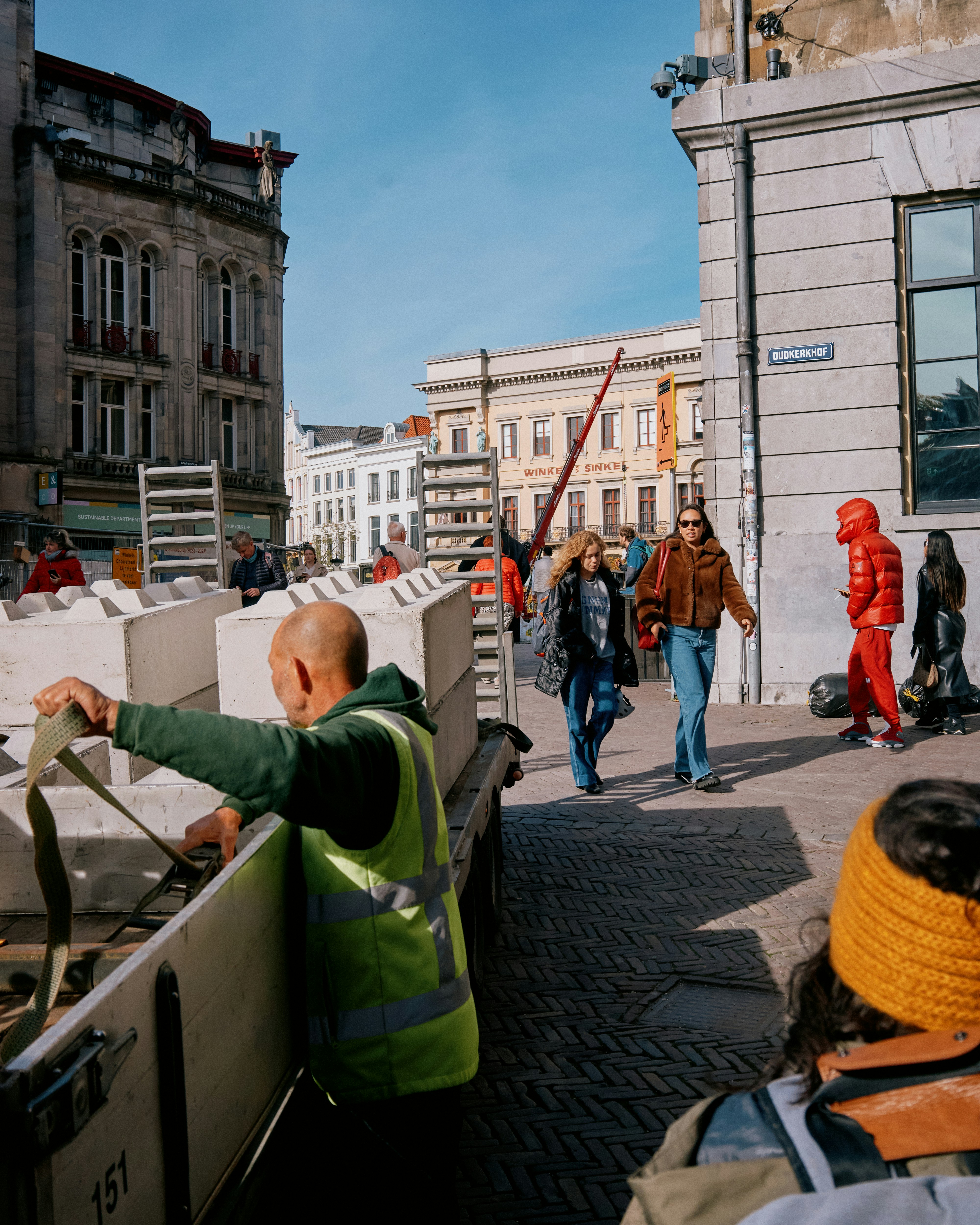 A group of people walking down a street next to tall buildings