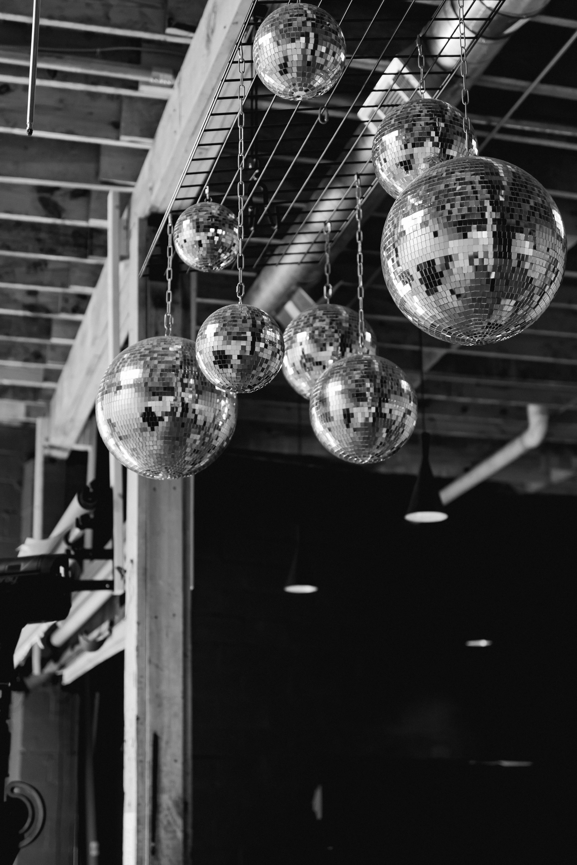 A black and white photo of disco balls hanging from a ceiling