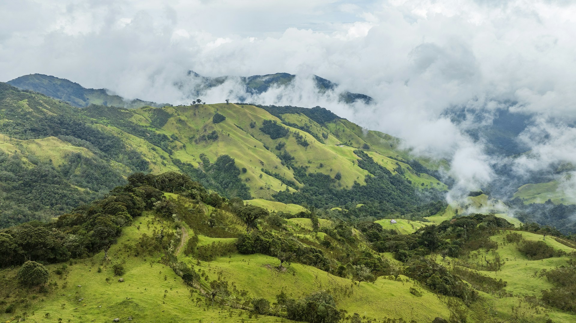 A lush green hillside covered in lots of clouds