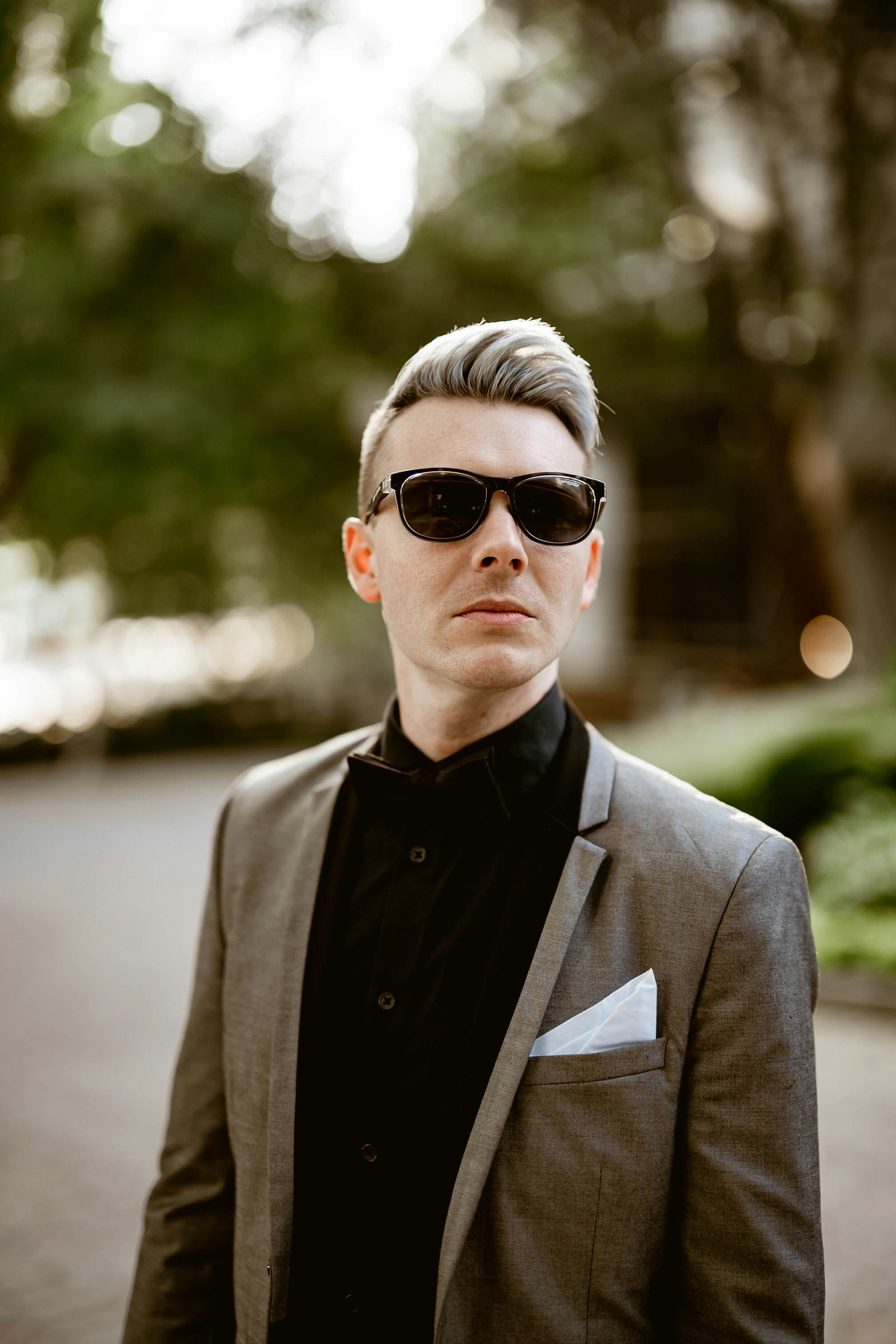 A man in a suit and sunglasses standing on a street