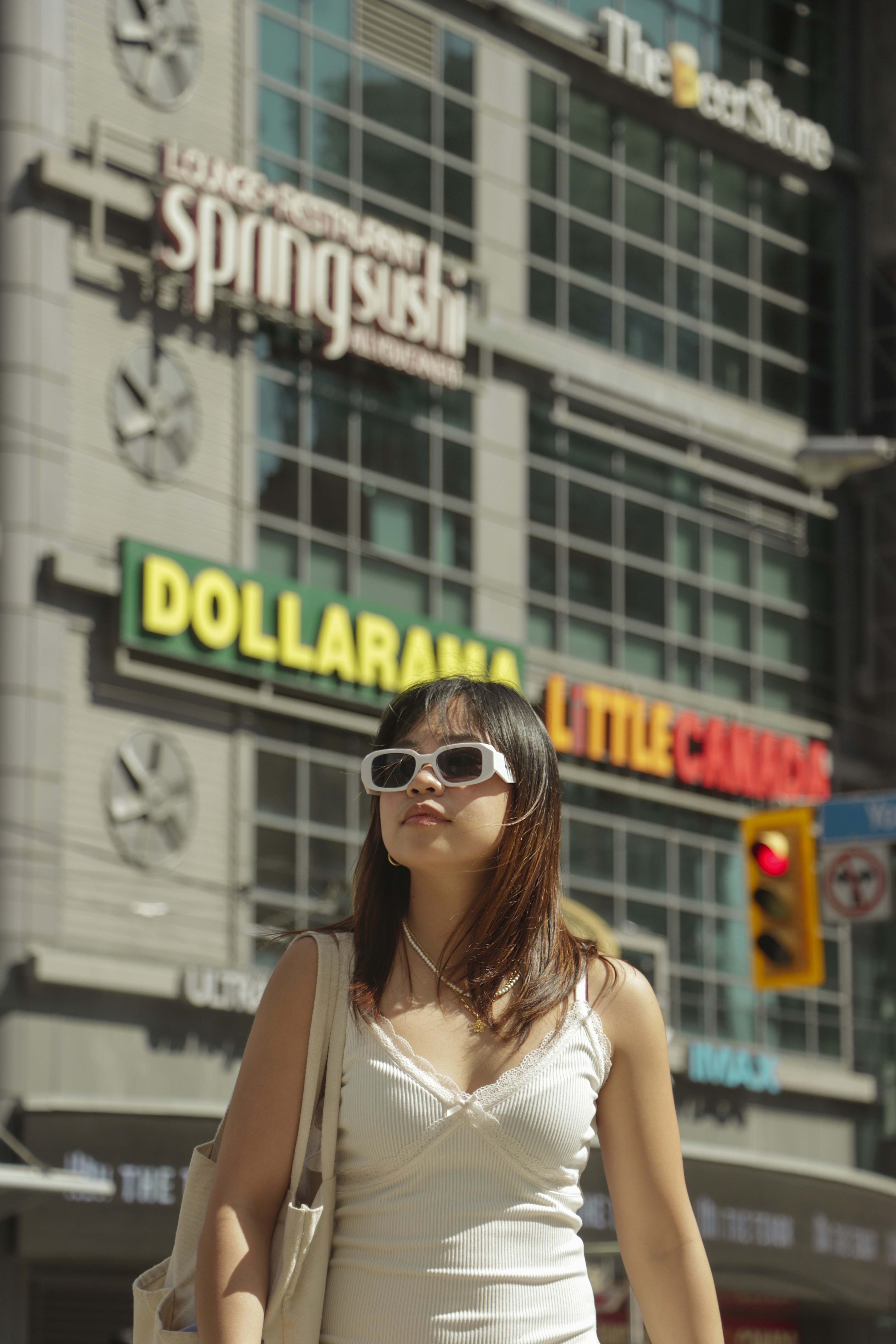 A woman in a white dress is standing in front of a building