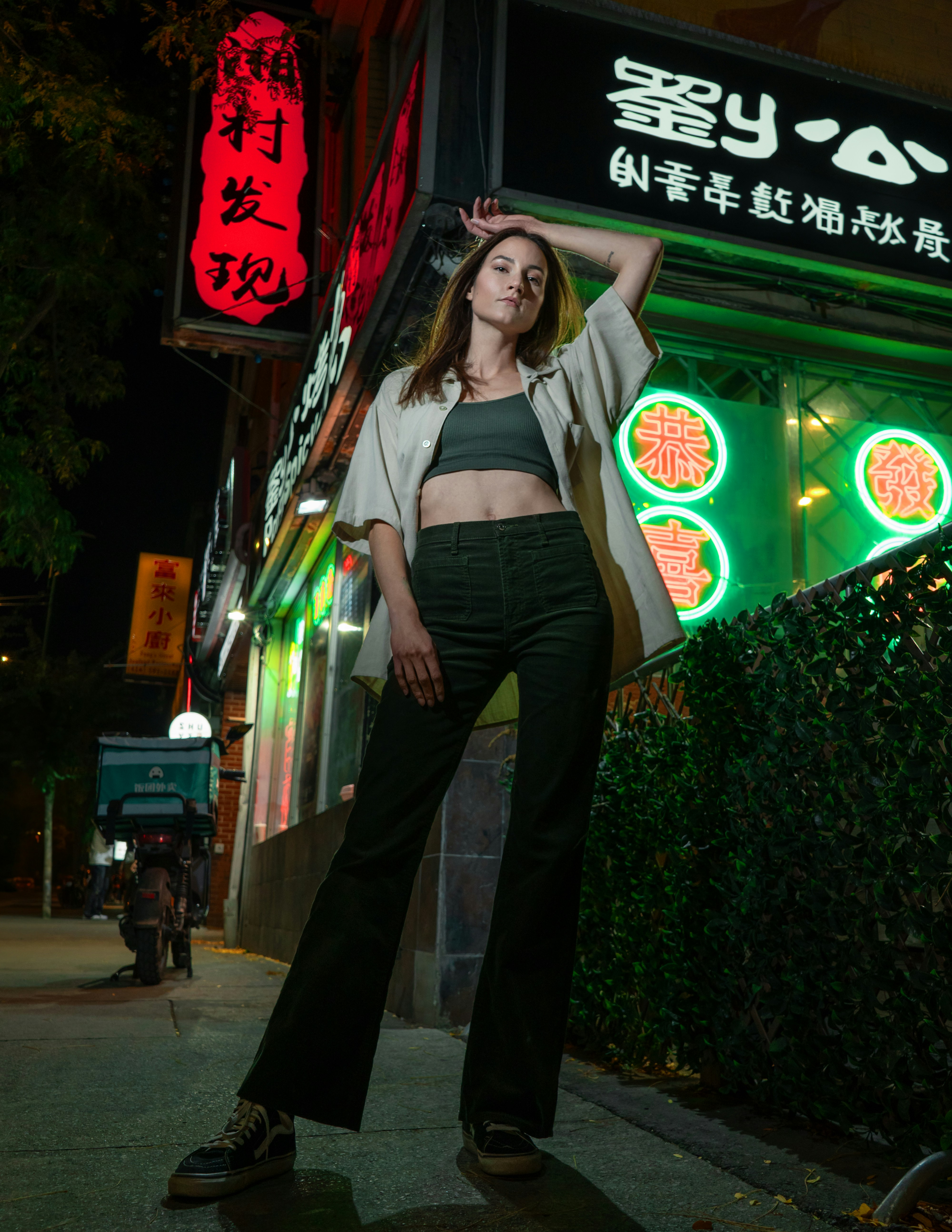 A woman standing in front of a store at night