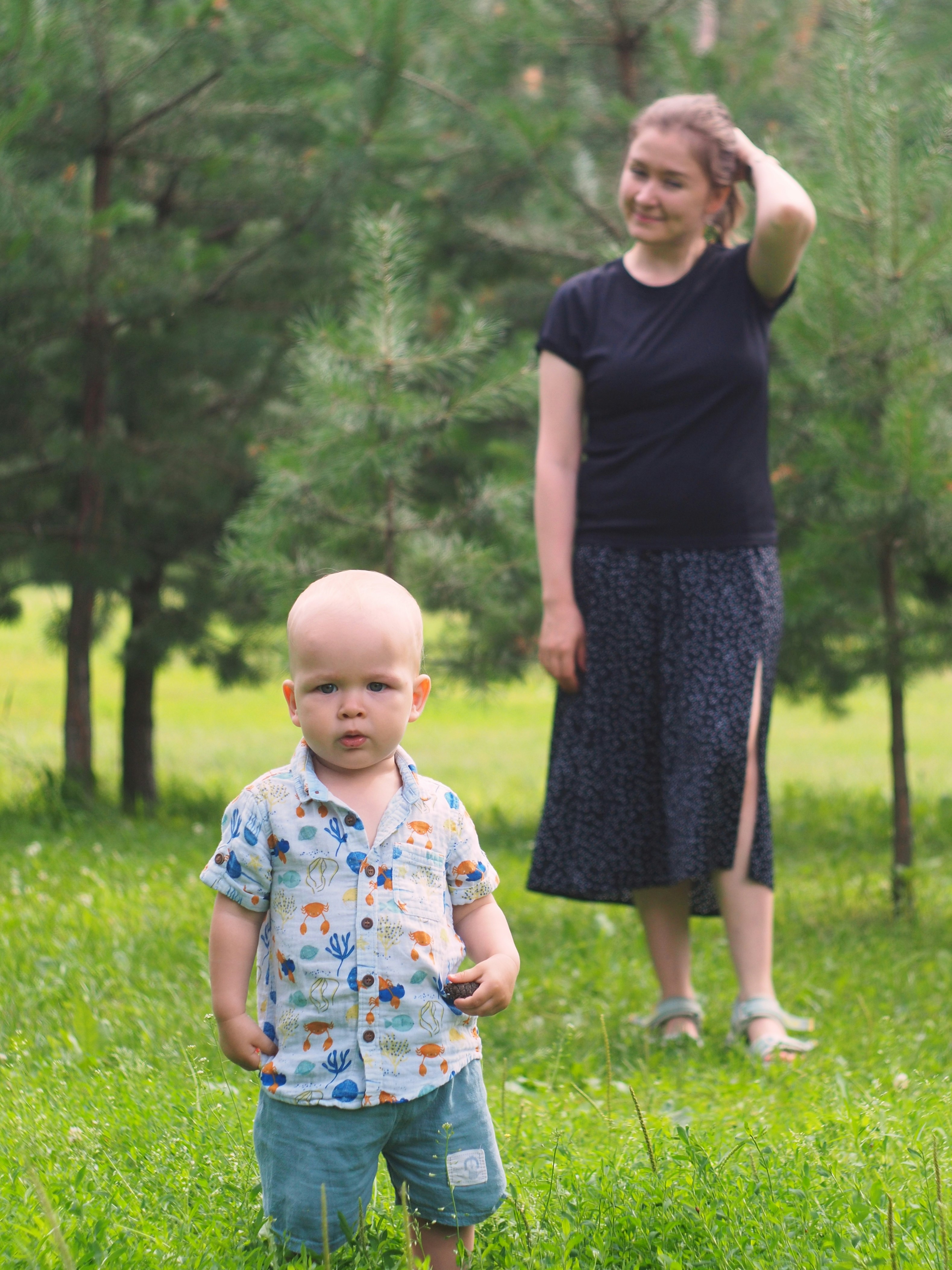 A woman standing next to a little boy in a field