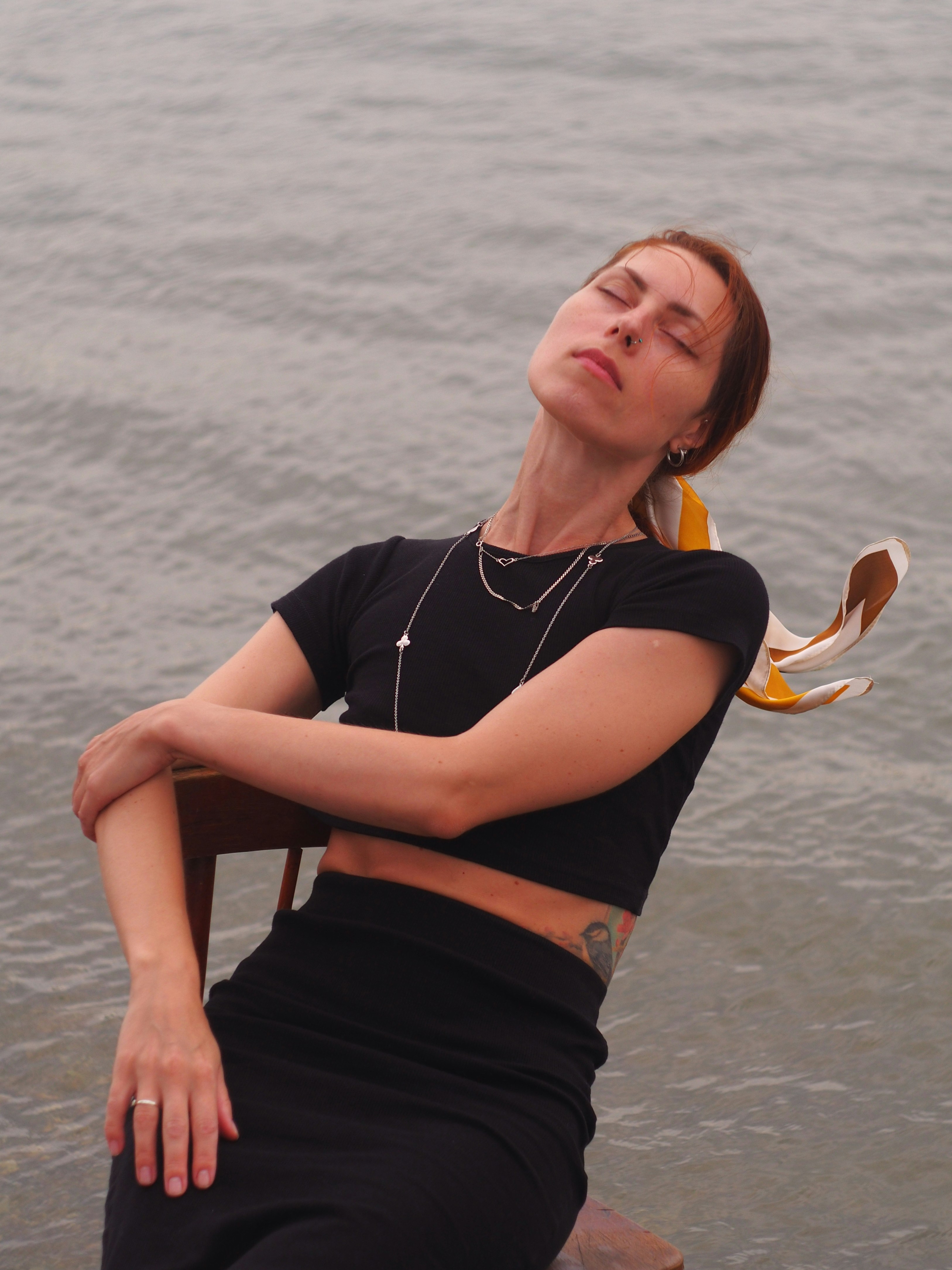 A woman sitting in a chair by the water