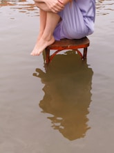 A woman is sitting on a chair in the water