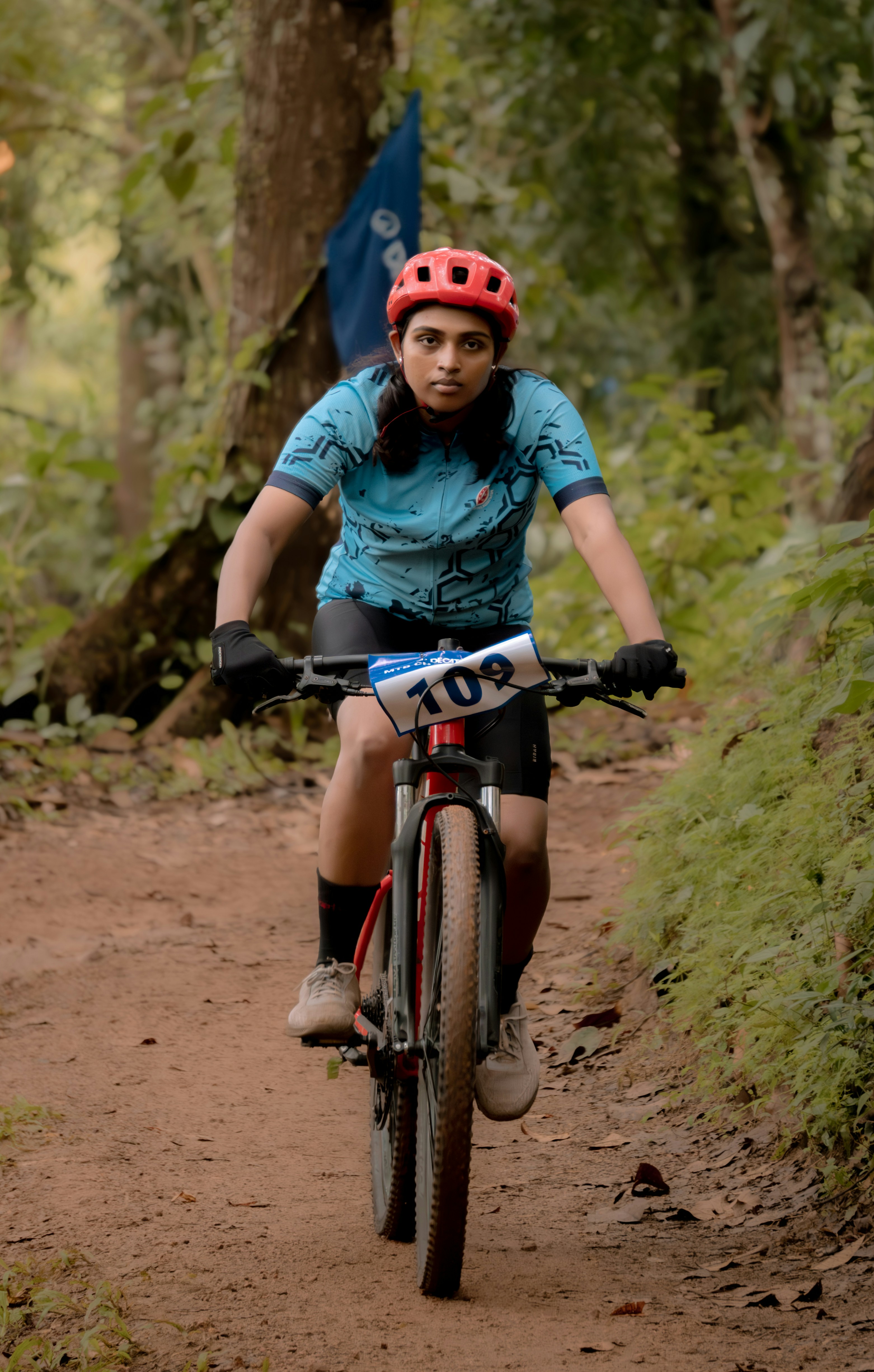 A woman riding a bike down a dirt road