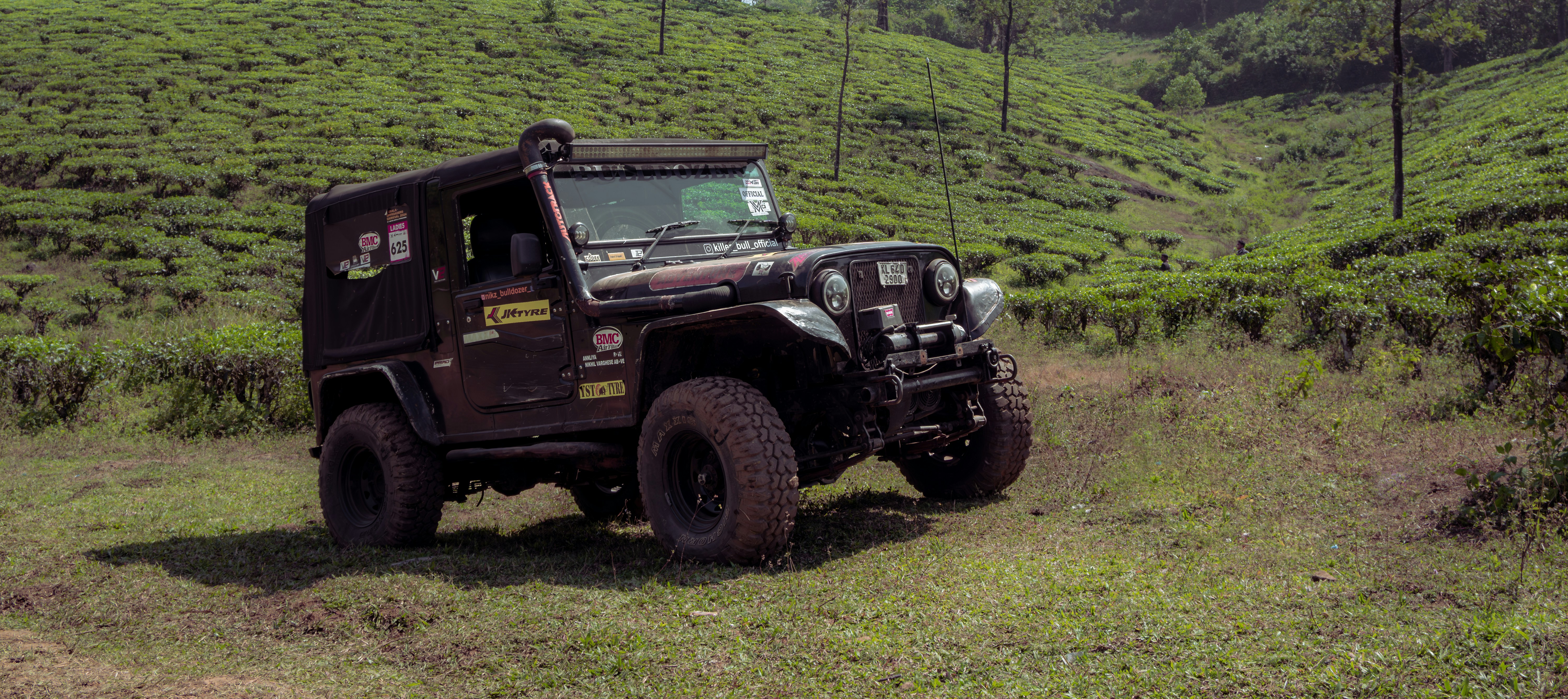 A jeep driving through a lush green hillside