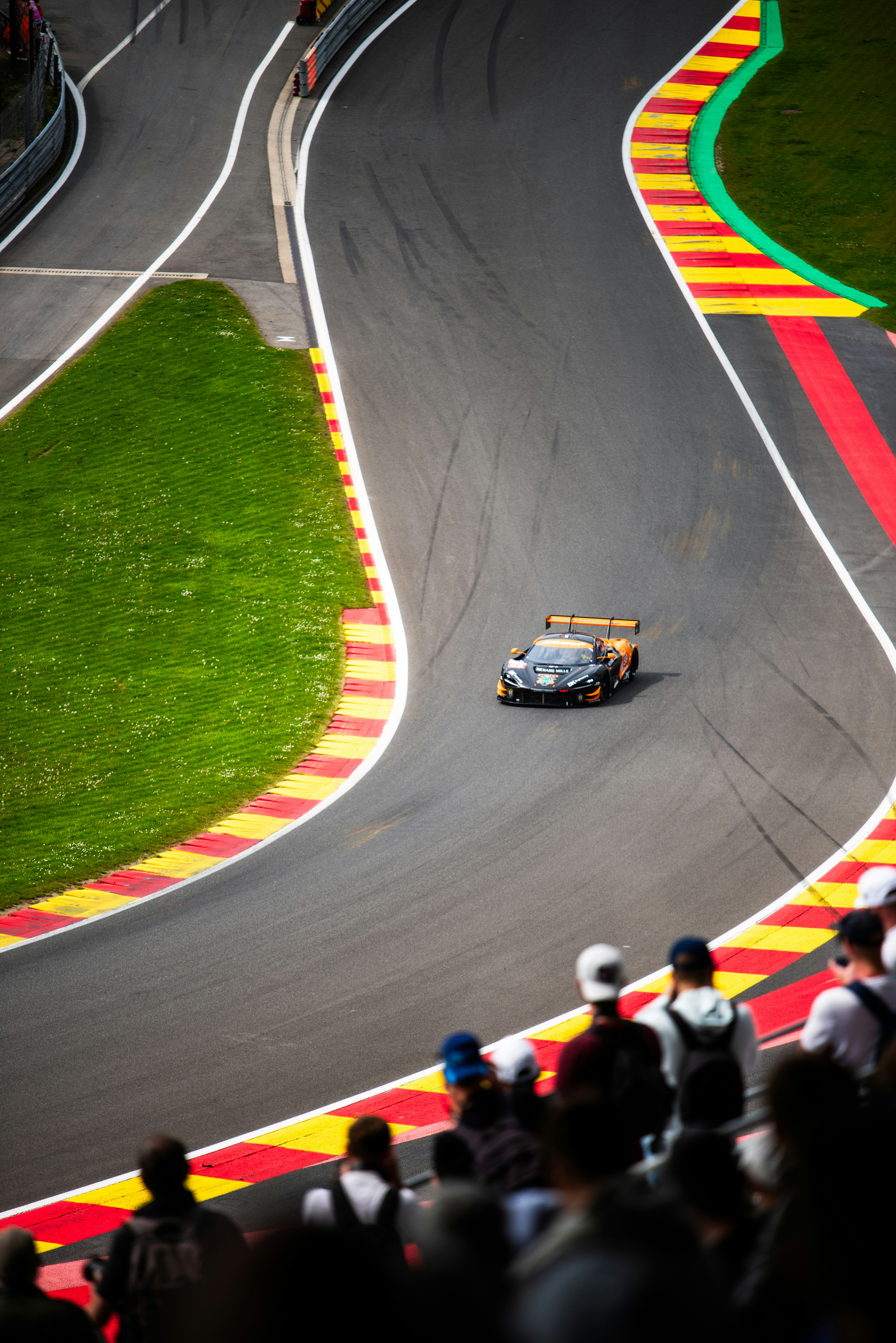 A car driving down a race track with a crowd watching