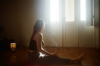A woman sitting on the floor in front of a window